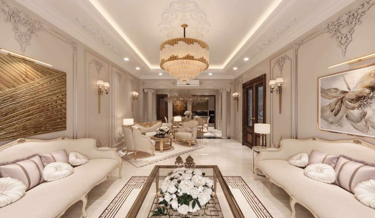 Luxury living room interior design in Vizag featuring elegant cream sofas, gold chandelier, decorative wall panels, marble flooring, and premium classic home decor.