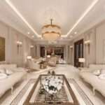 Luxury living room interior design in Vizag featuring elegant cream sofas, gold chandelier, decorative wall panels, marble flooring, and premium classic home decor.